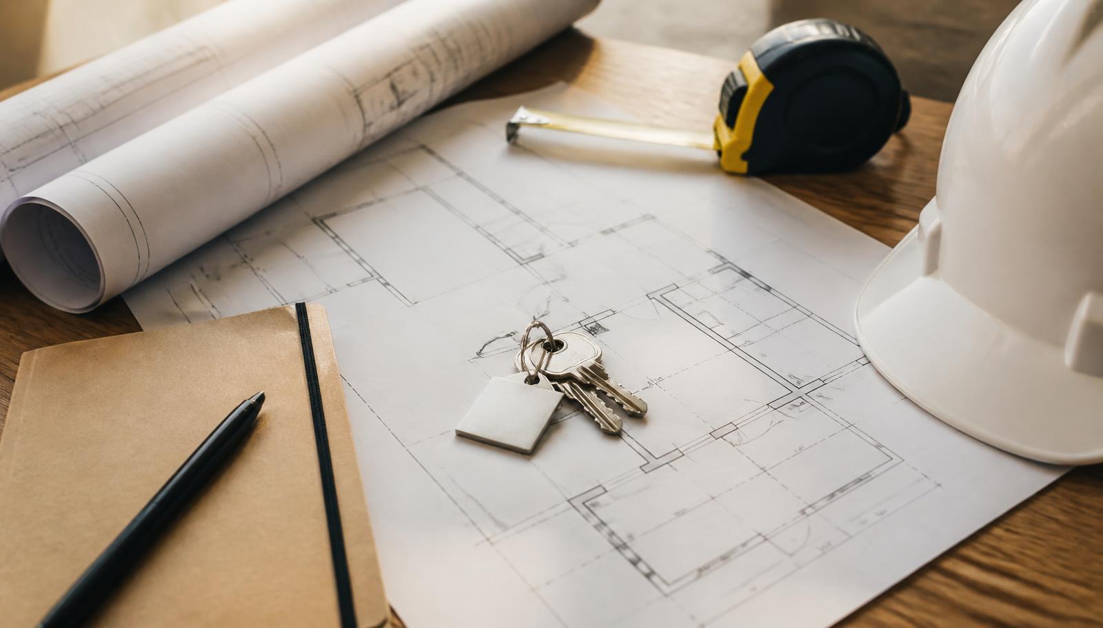 Rolled commercial site plans, keys and a folder of lease materials on a work table